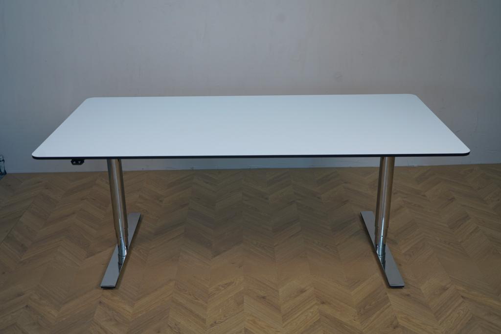 Triumf hæve-sænkebord set forfra med hvid HPL-bordplade, sorte affasede kanter og runde ben. Elegant elektrisk skrivebord i 160x80 cm.